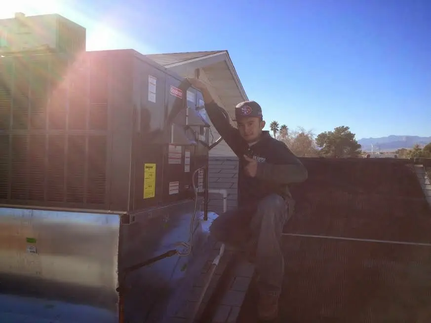 HVAC technician performing AC Tune-Up on a rooftop unit in El Centro